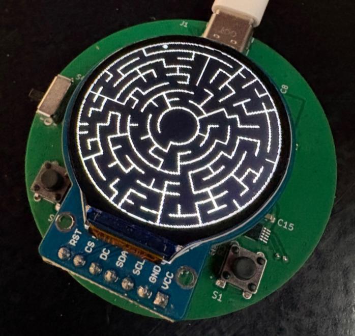 The assembled board powered on, running the maze on its round OLED display.